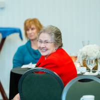 An alumna smiling from across the room at the Reunion Dinner.
